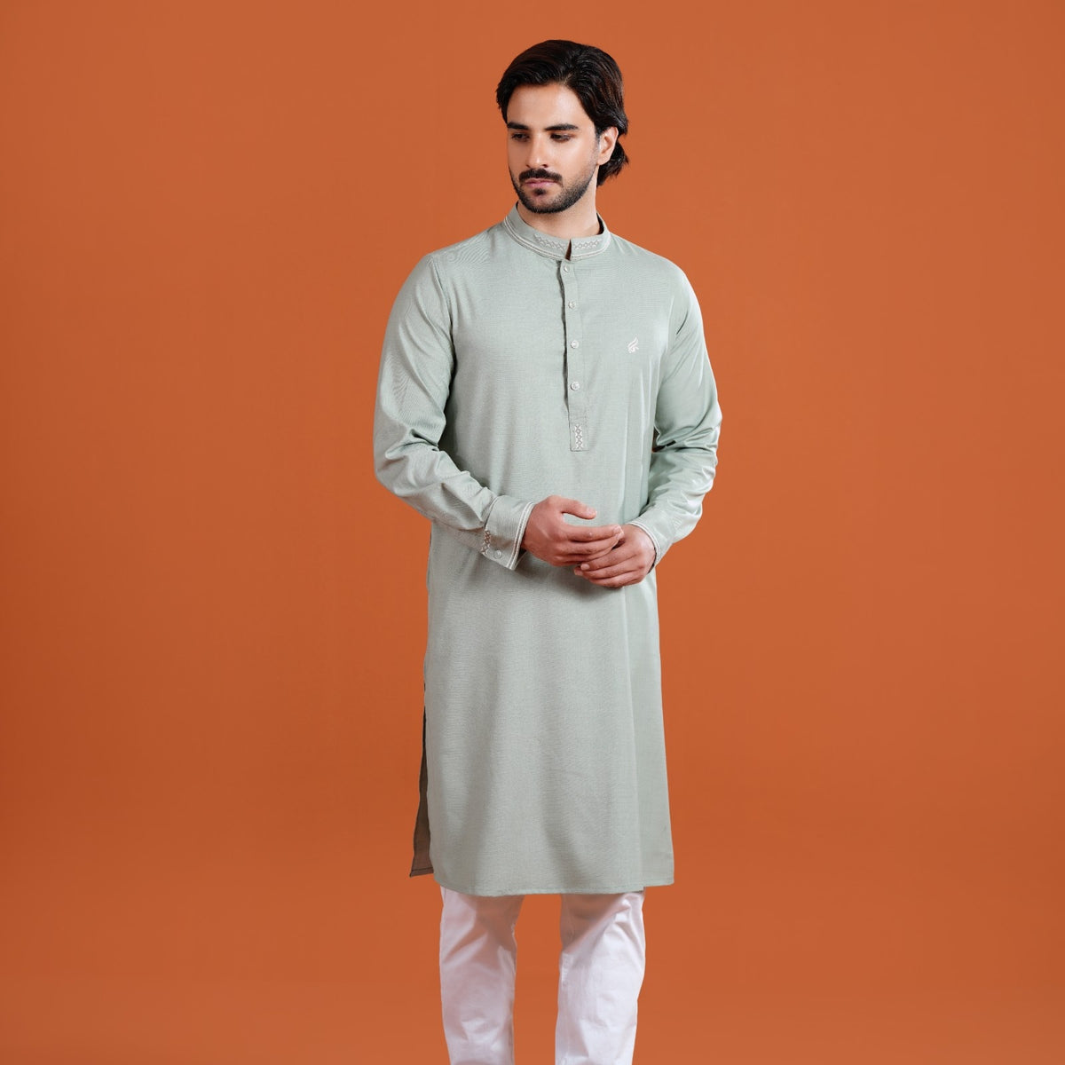 Man wearing a yamaan panjabi with white pants against an orange background