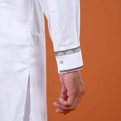 Close-up of a white yamaan panjabi with decorative cuffs against an orange background