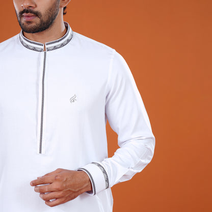 Man wearing a white traditional yamaan panjabi with intricate detailing on an orange background